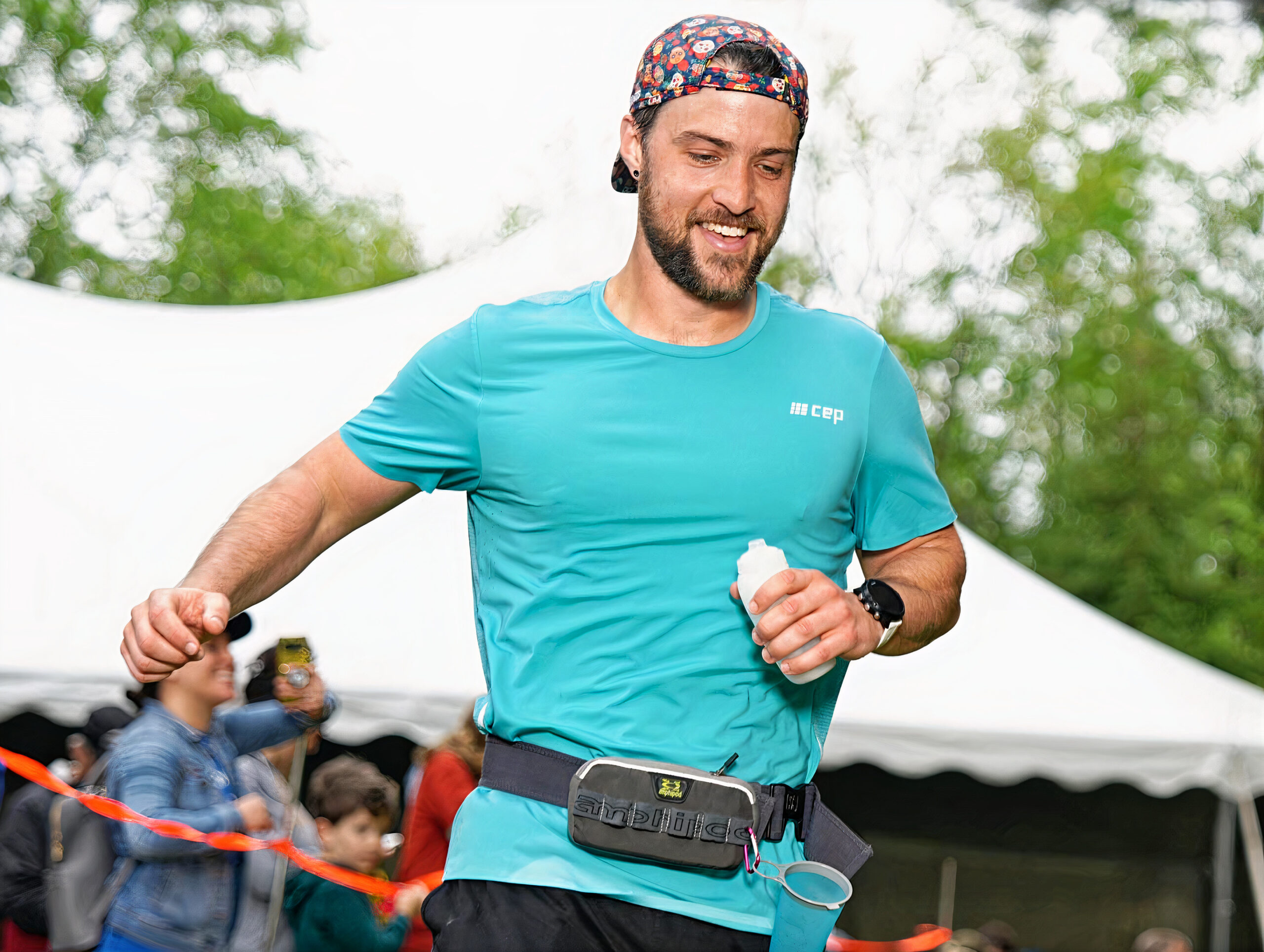 Coach Nick Savin, smiling as he crosses the finish line at a running event, embodying the vitality and approachability central to Run Strength Academy's coaching philosophy.